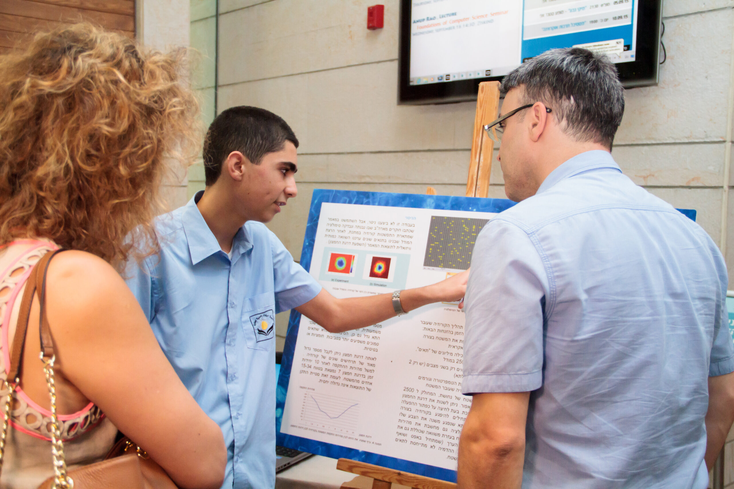 A student presenting a research poster to two people