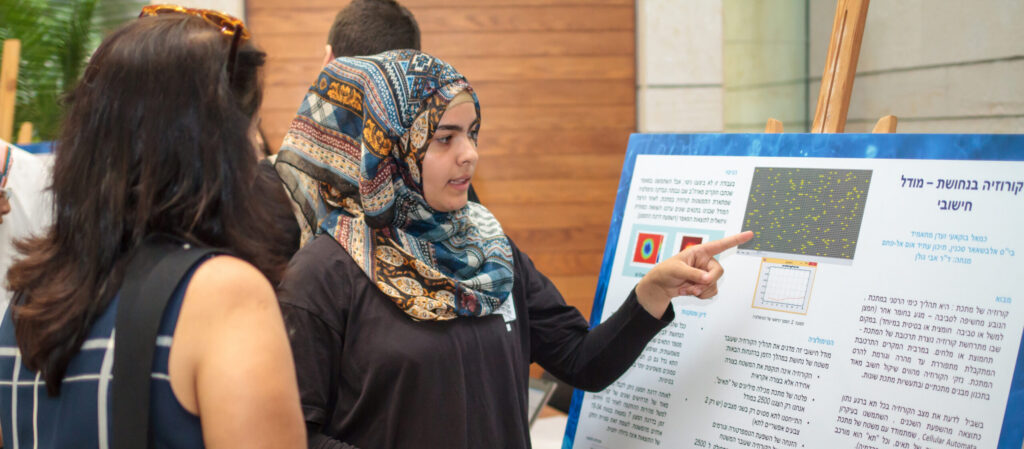 A student presenting a research poster to two women